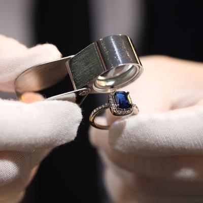 A jewelry appraiser using a loupe to evaluate a bejeweled ring.