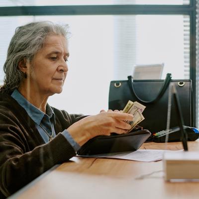 An elderly person preparing cash for a deposit transaction in a bank.