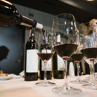 Wine being poured into glasses by a somelier at a restaurant.