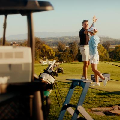 Golf players high five in the air during a game.
