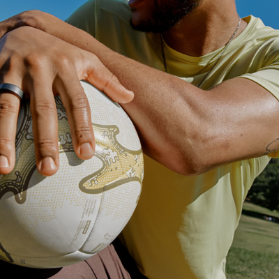 A person wearing a smart sleep ring while holding a ball outdoors.
