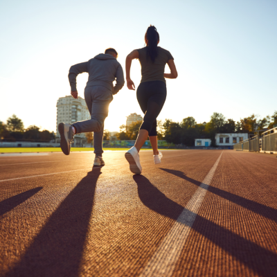 Two people running on an empty track at either sunrise or sunset.
