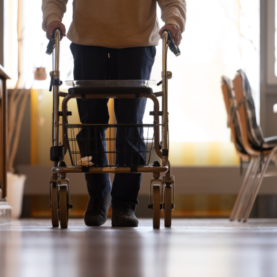 An elderly man using a walker in a nursing home.