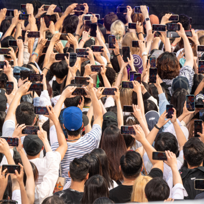 A crowd of people holding phones up in the air.