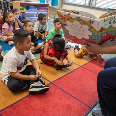 A teacher reading to small children in a classroom.