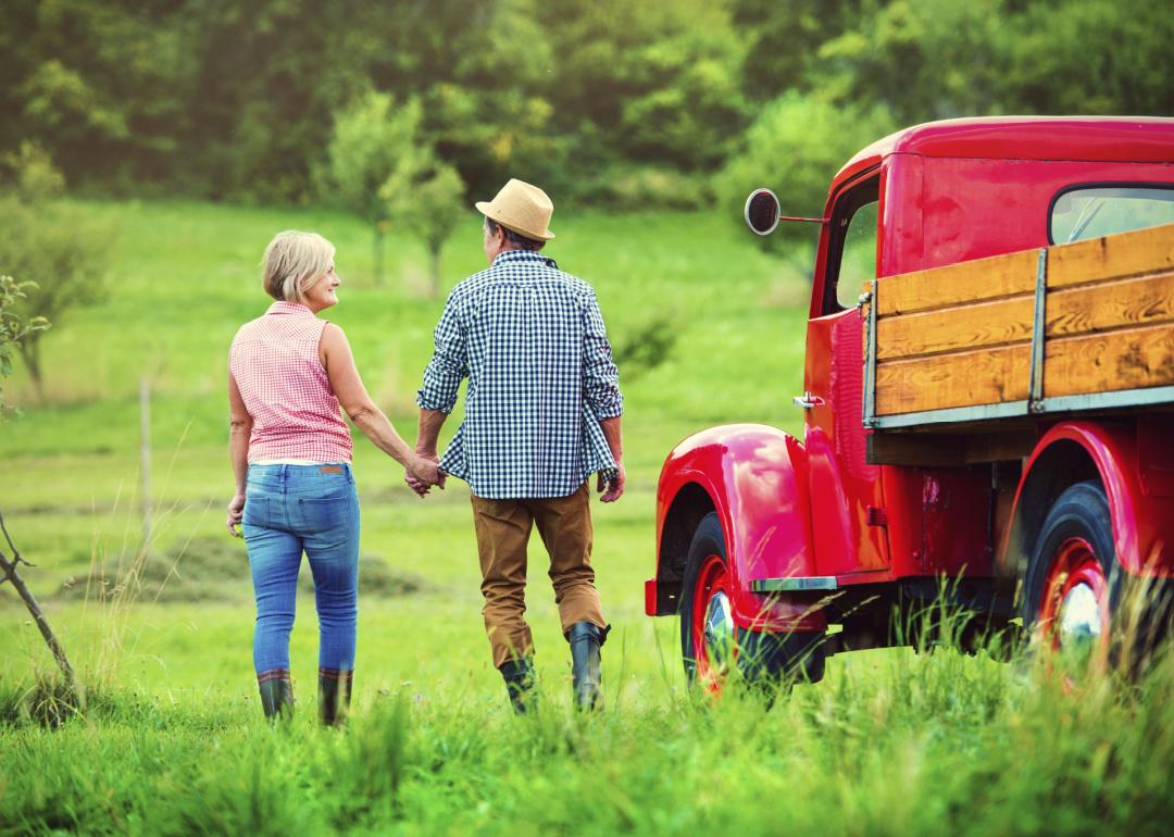 Senior couple walking by a red truck on a farm.