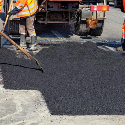Road workers repairing a street with new hot asphalt