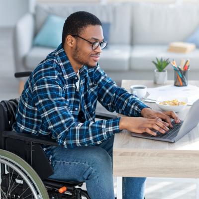 Man in wheelchair using laptop.