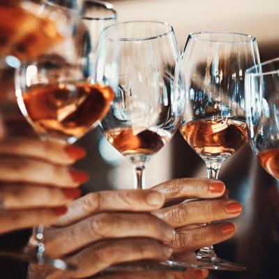 Six hands holding wine glasses for a toast.