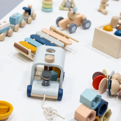 A person's hand placing a wooden toy on a table of wooden toys for baby and infant-aged children.