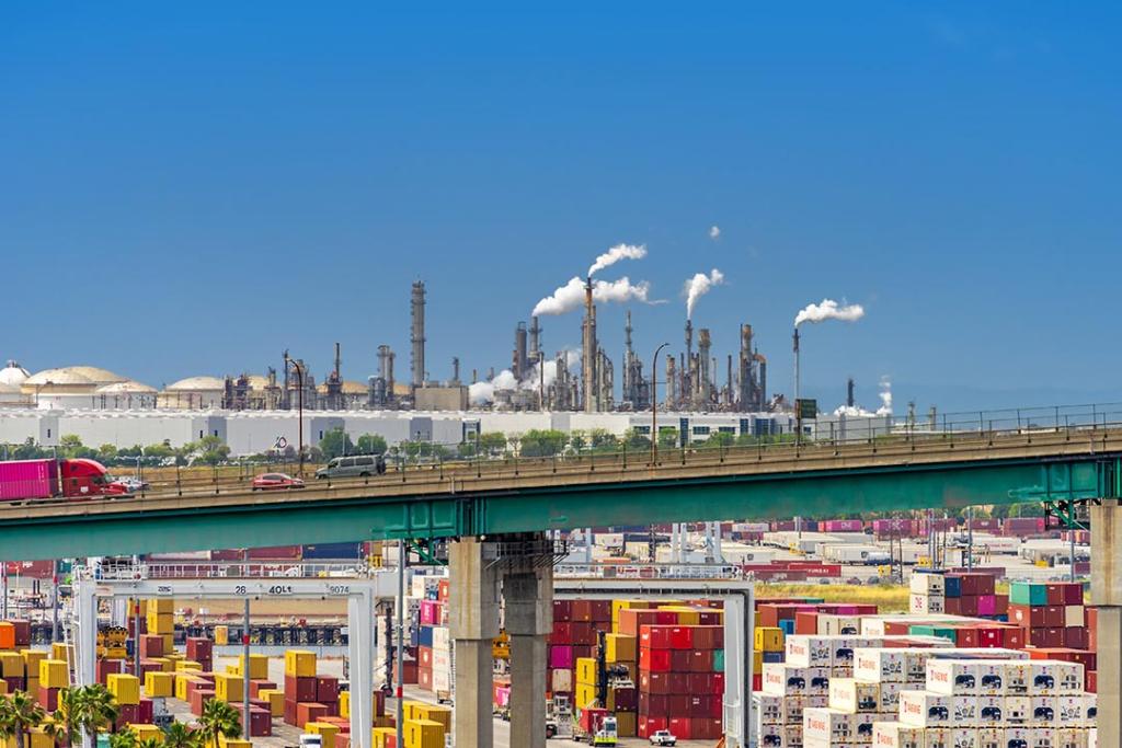 Vincent Thomas Bridge in the foreground and a oil refinery with smoke stacks in the background as seen from the Port of Los Angeles in San Pedro, California.