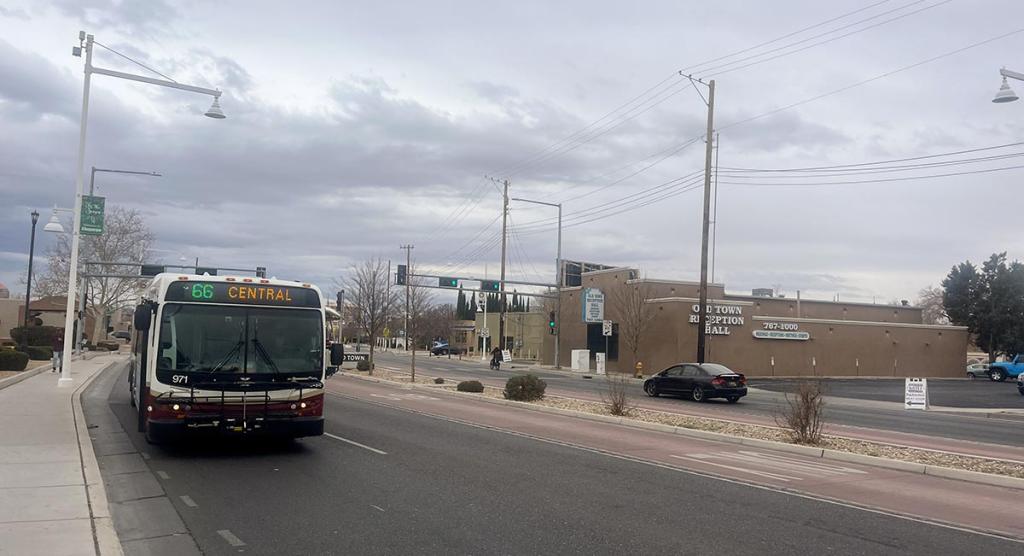 Bus driving on road toward viewer with destination "66 Central" showing, grey cloudy day in the background.