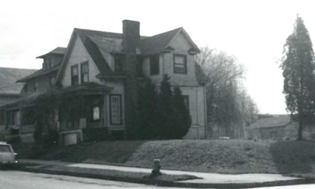 Black-and-white photo of a two-story home with a pointy roof owned by Mike Hepburn’s grandparents. 