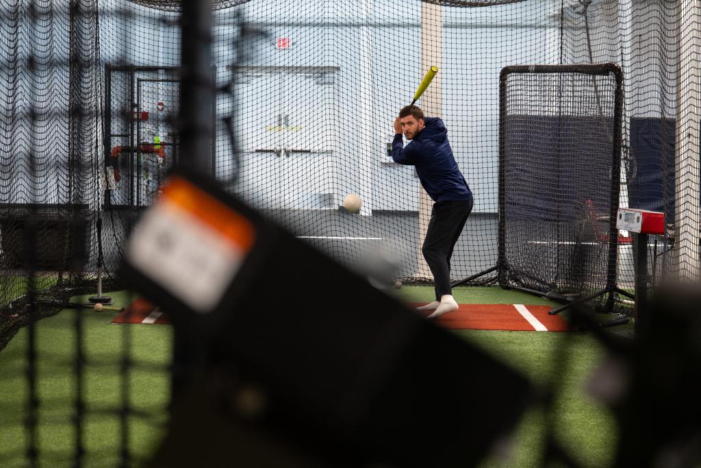 A student practicing for baseball in a sports gym in Mount Mercy University.