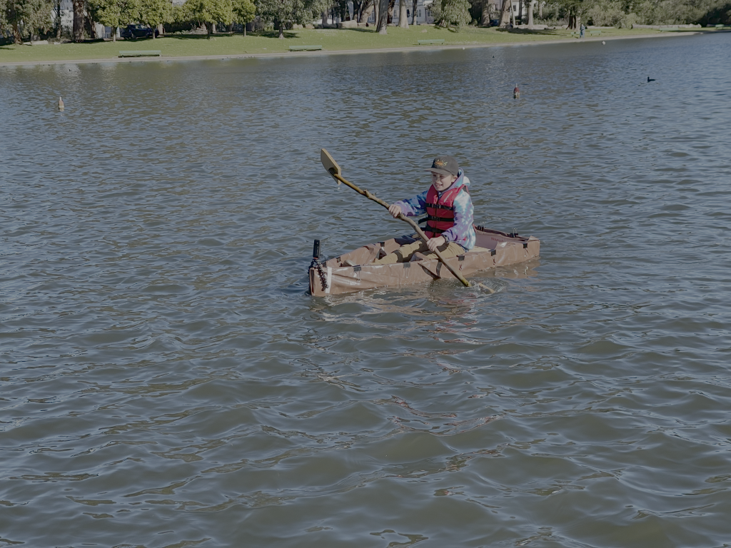 An 8-year old boy paddling a boat in water made by Brightworks students.
