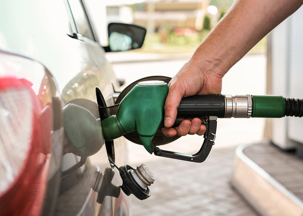 A green-handled gas pump filling up a car.