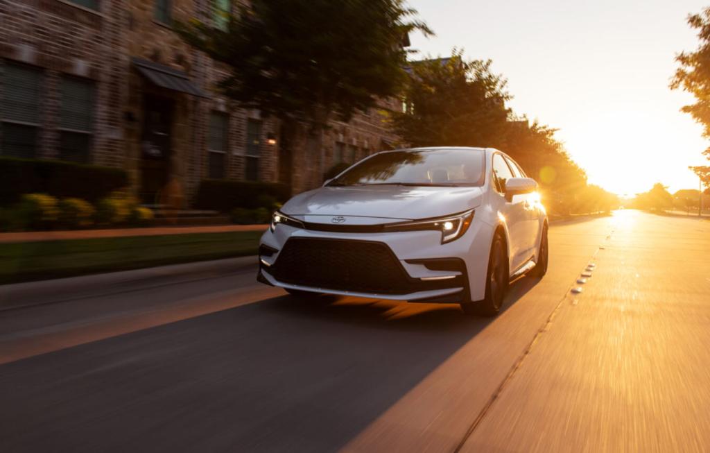 Silver 2024 Toyota Corolla driving on the road with sunset in the background.