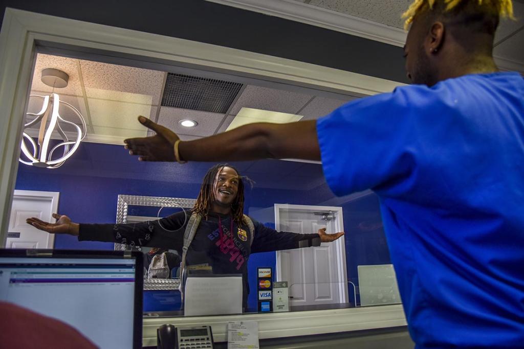 Jon'Aric Nathaniel is greeted by intake manager Regi Stevenson at Open Arms Healthcare Center on Tuesday.