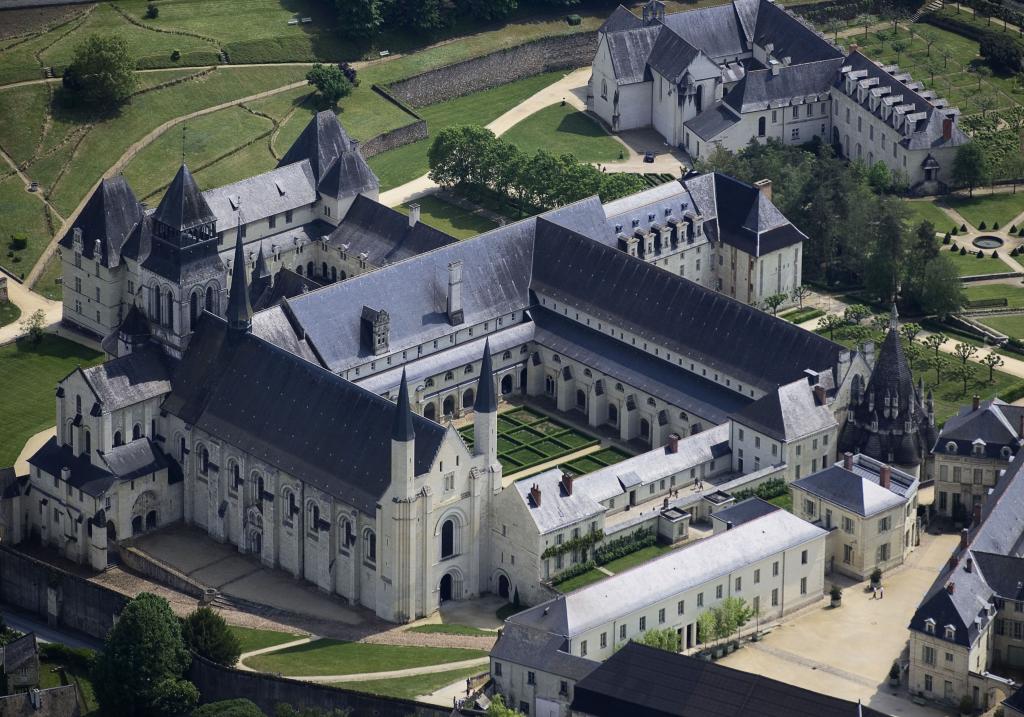 Aerial view of the Fontevraud L’Ermitage an imposing fortress-looking building with spires and pointed roofs.