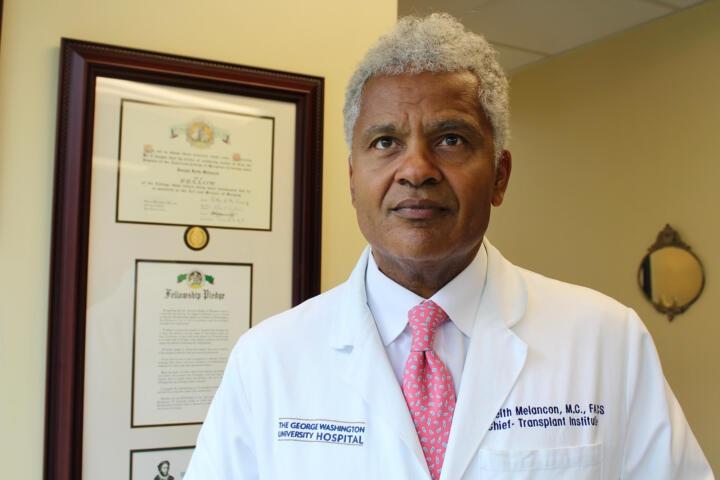 Dr. Joseph Keith Melancon, director of transplantation at the George Washington University Hospital stands in an office in front of a framed diploma.