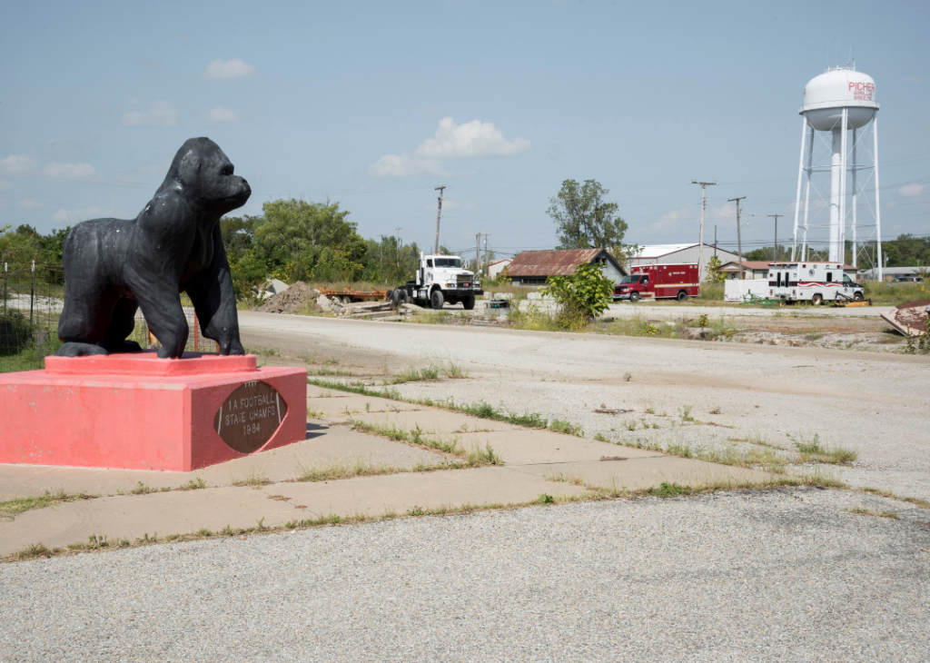 A gorilla on a pedestal on the side of Route 66 with the Picher, Oklahoma, water tower in the background.