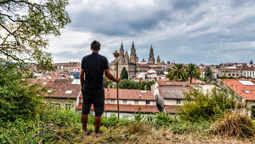 Hiker at the end of trail, reaching a view of Santiago de Compostela.