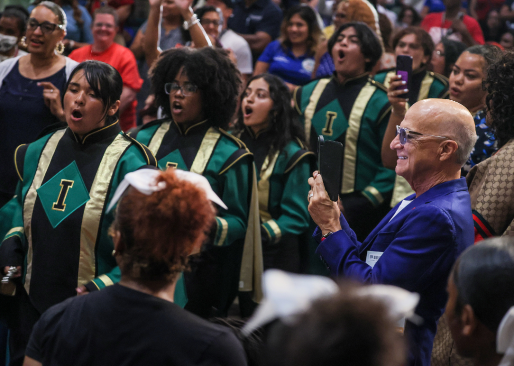 Record producer/philanthropist Jimmy Iovine, surrounded by people, takes a video with his phone of the Inglewood High marching band as they perform. 