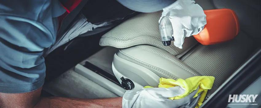 A detailer cleaning a leather seat of a car.