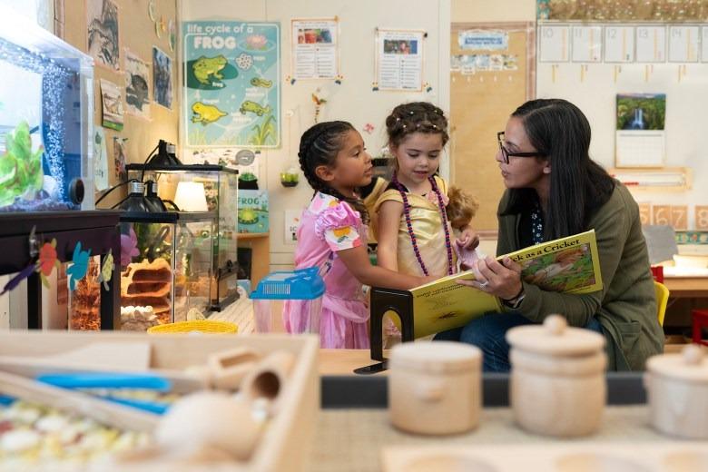 Transitional kindergarten instructional assistant Nancy Espino reads a book about crickets to two  children at Silverwood Elementary School in the Mt. Diablo Unified School District in Concord.