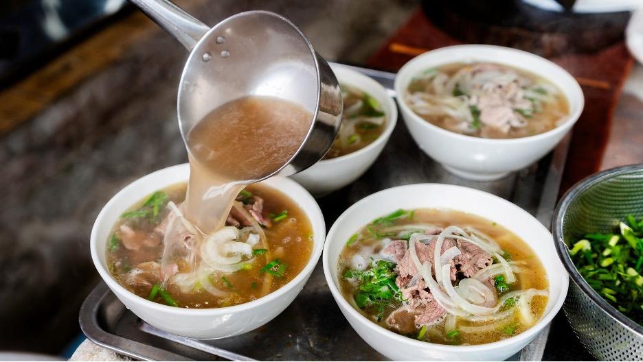 A rich broth ladled onto bowls of Pho.