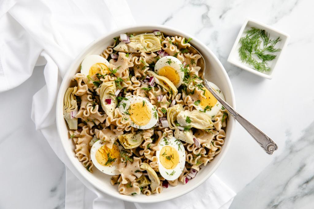 Top-down view of bowl of egg pasta salad using lasagna noodles, garnished with dill.