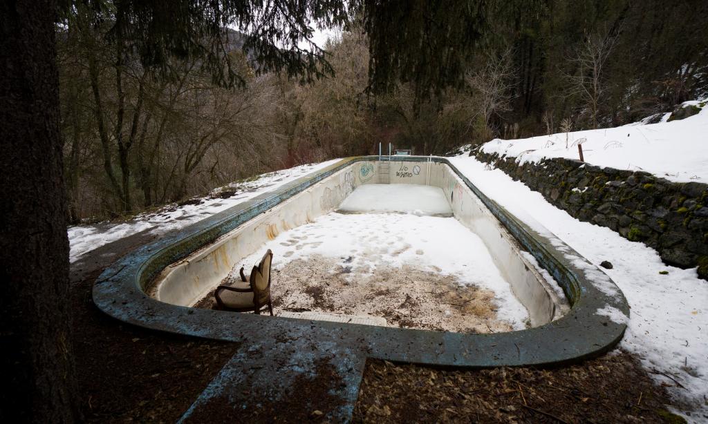 The empty outdoor swimming pool contains a broken chair and a snow-covered bottom at the Logan Canyon property that was once St. Ann's Retreat.