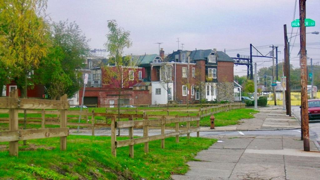 View of 1600 North 54th Street after clean-up. Concrete railings have been replaced by wooden fencing, lot is free of litter and grass is green.