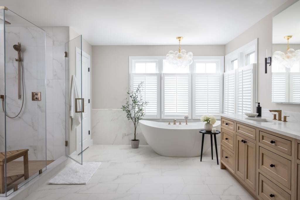 Bathroom with white marble floor and shower tiles and a standalone soaking tub.