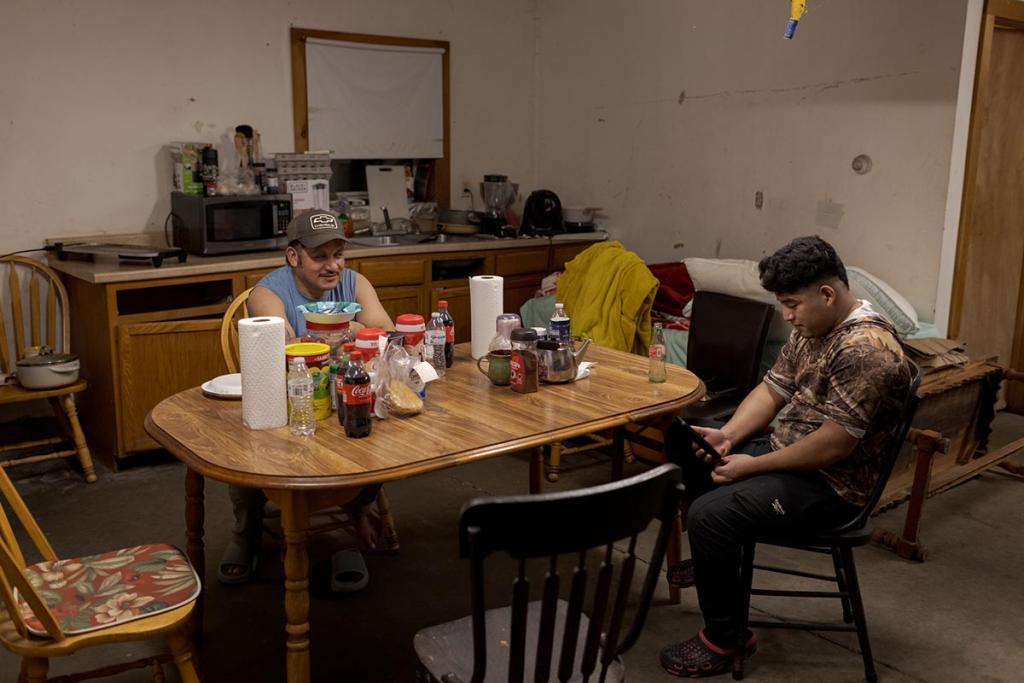 Nicolas and his co-worker rest after finishing an evening milking shift on the dairy farm where they live and work.