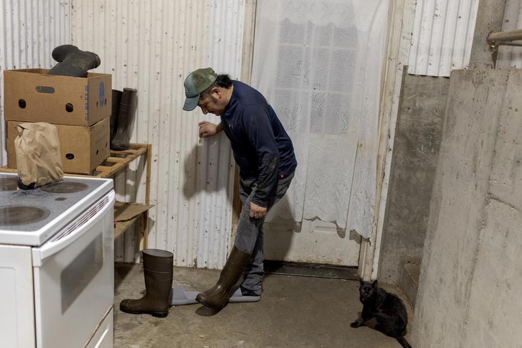Nicolas, a 49-year-old farm worker from Mexico, takes off his muck boots at the end of an evening milking shift outside the door to the living quarters that he shares with two other workers from Mexico.