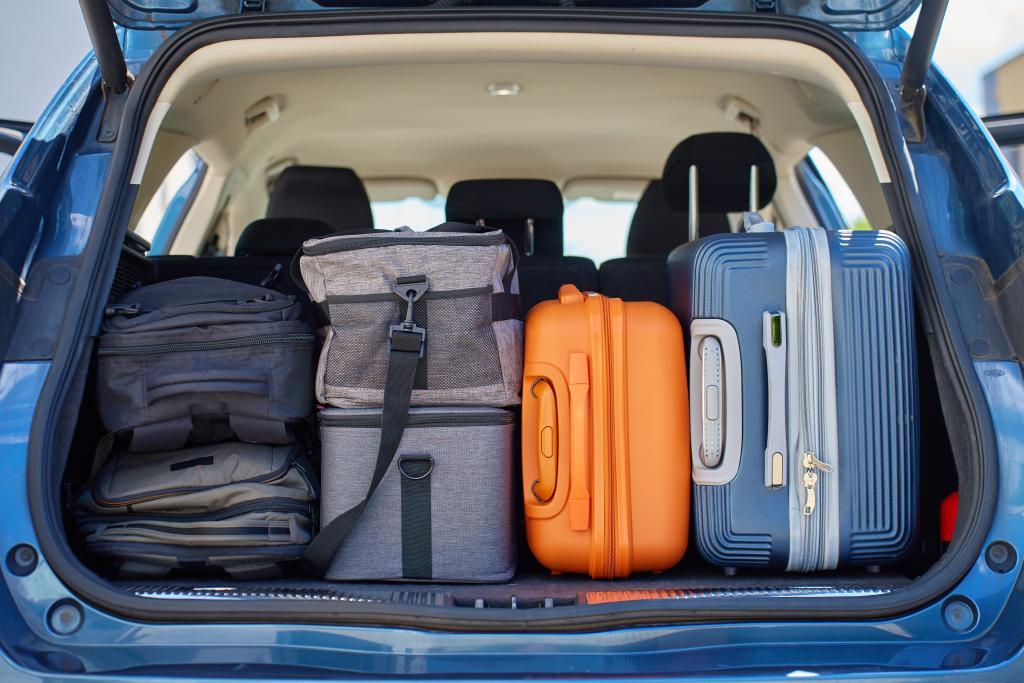 A car trunk packed with backpacks, bags, and suitcases before a road trip.