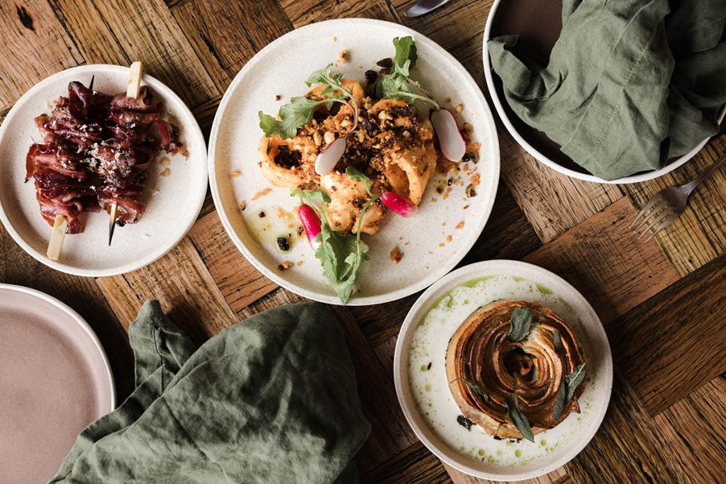 Top down view of dishes on a wooden table that feature truffles, with two green napkins.