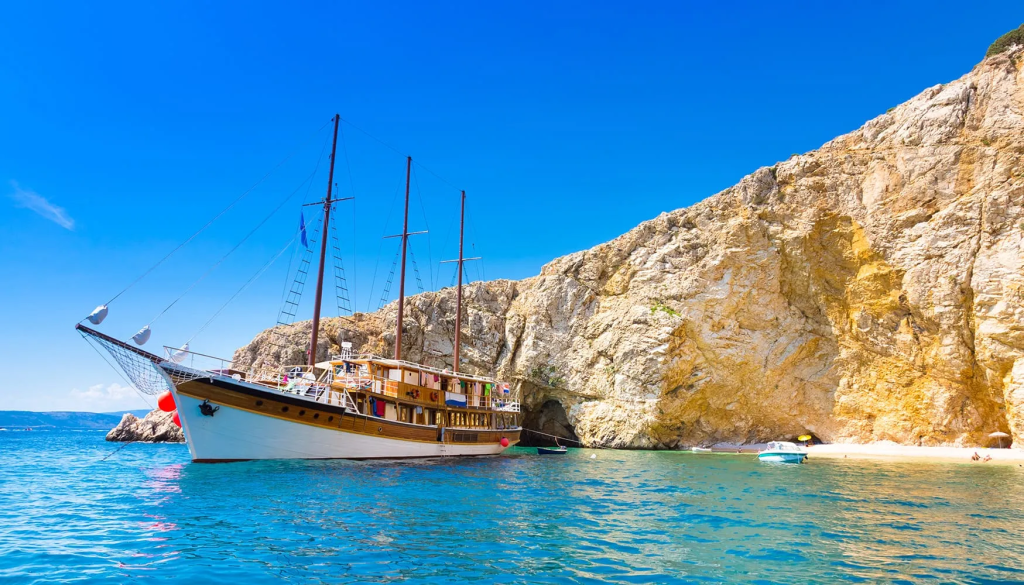 A wooden motor-sailing vessel anchored in a secluded cove in Croatia.