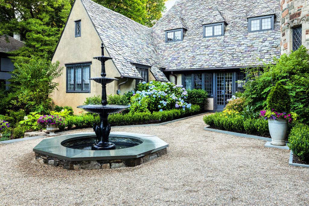 Front view of a house that has a courtyard inspired by French and Italian styles, it includes a circular space with a fountain in the middle.