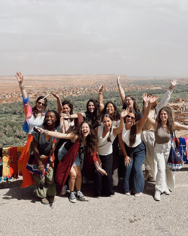 Young tourists posing for a photo with the desert landscape of Morocco as their backdrop.