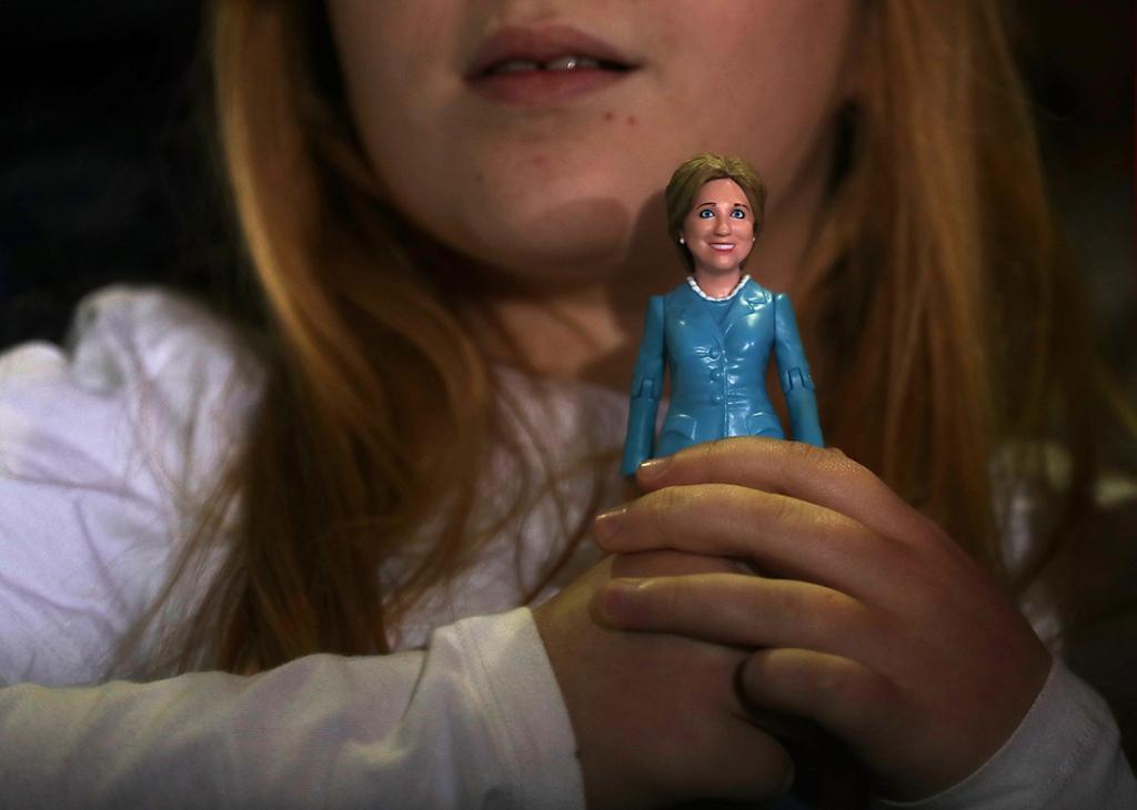 A young girl holding a doll of 2016 Democratic presidential nominee and former Secretary of State, Hillary Clinton.