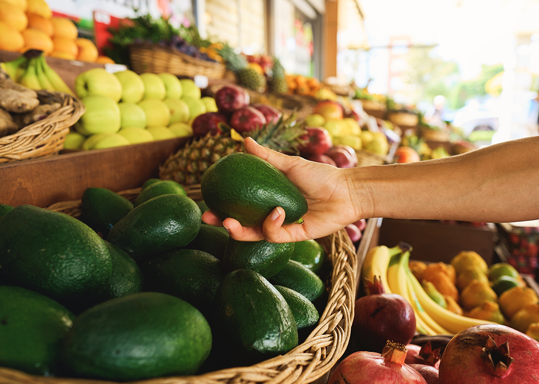 Person holding avocado in market.