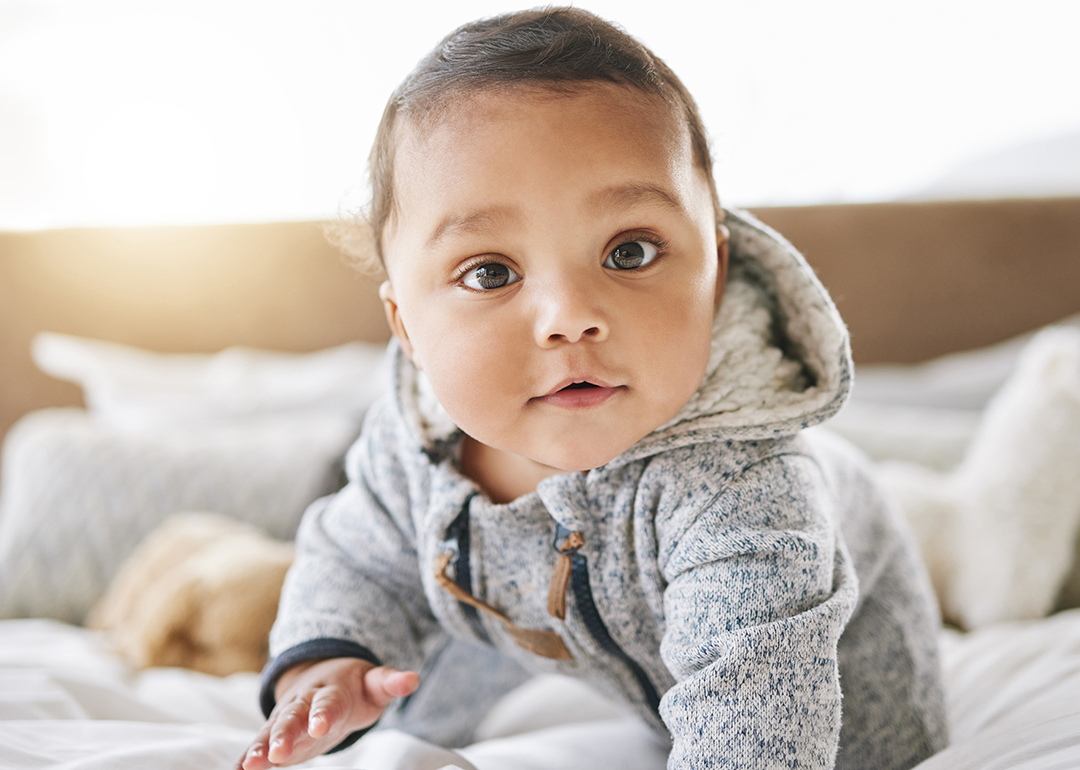 Brown eyed baby wearing fleece hoodie looking into camera.