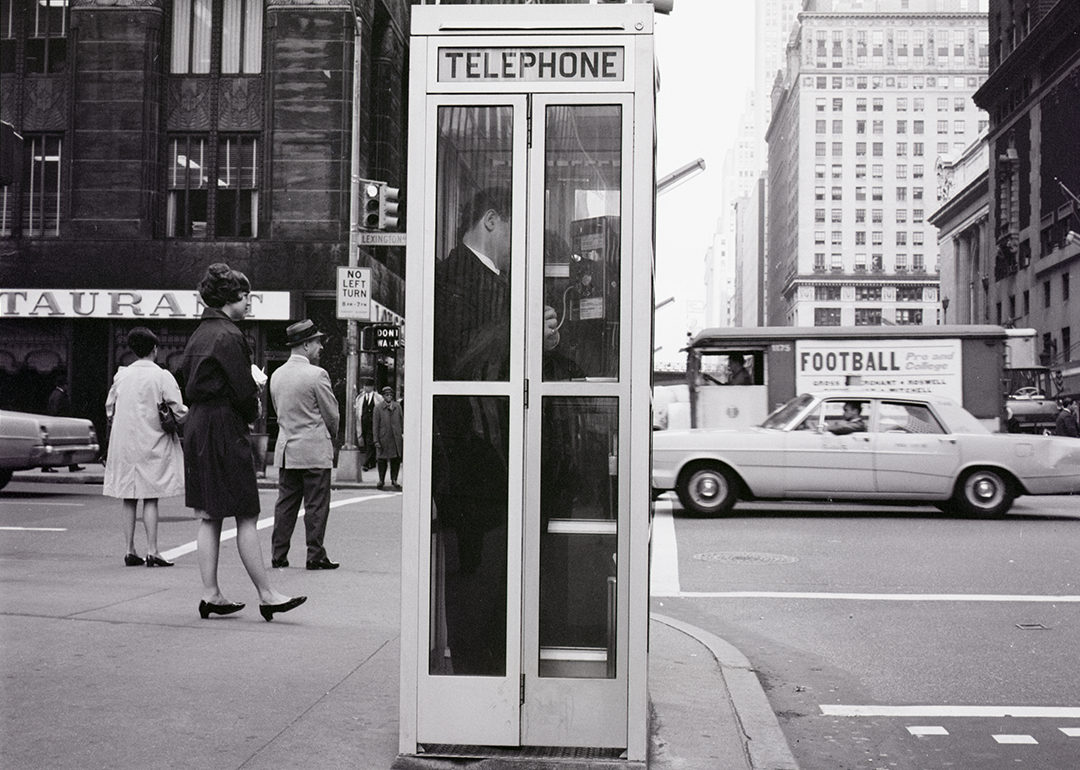 A vintage black and white photo of a telephone booth at 42nd Street and Lexington Avenue in New York City.