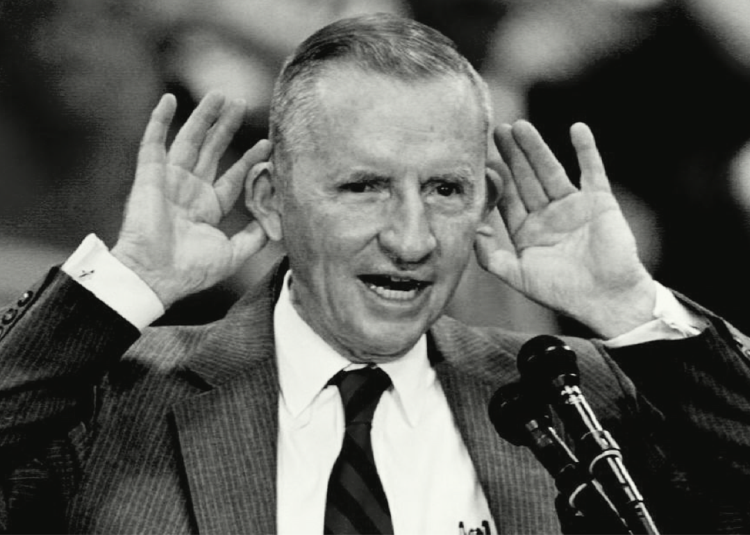 Ross Perot speaks with hands to his ears.