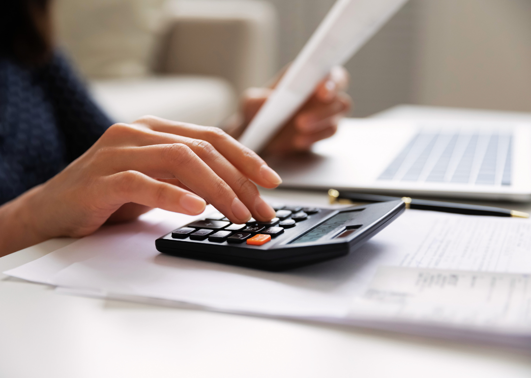 Closeup of hands on calculator paying bills.