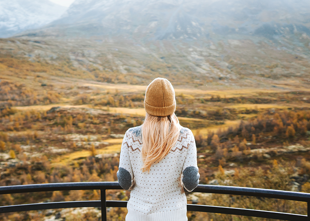 Woman in sweater looking out over dramatic fall landscape.