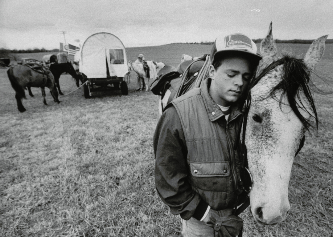 Young man nuzzling up to his horse in open field while reenacting the Trail of Tears journey in 1988.