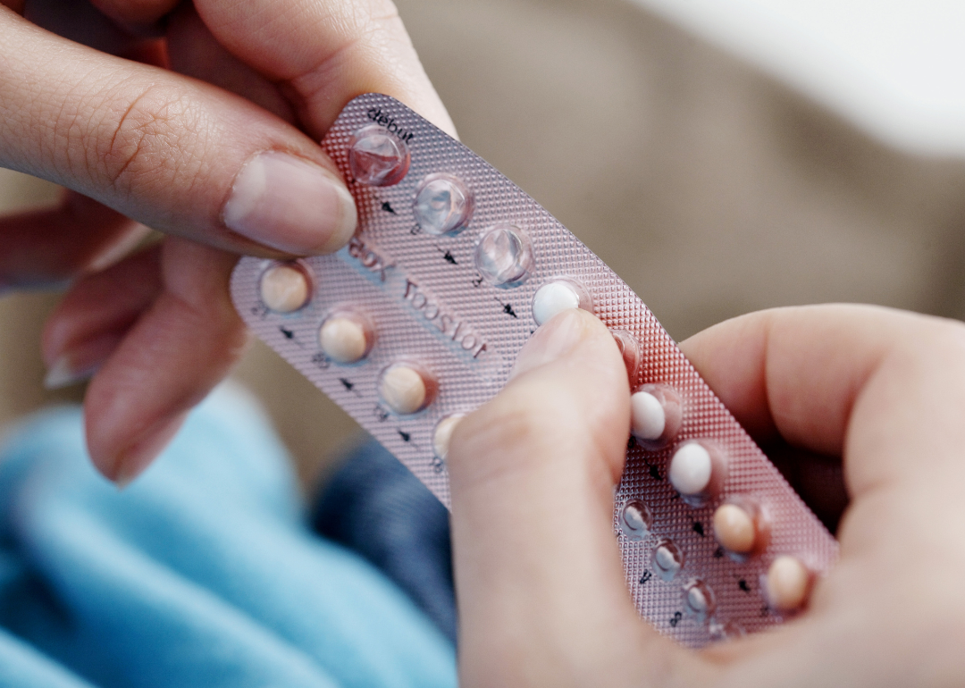 Close-up of hands holding oral contraceptive pills.